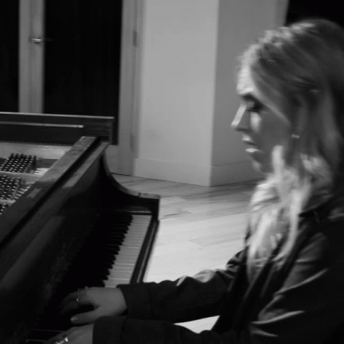 a young blond woman is playing a piano in a black and white po
