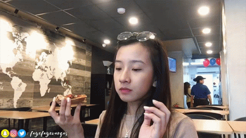 an asian woman holding two electronic devices in one hand and staring at the camera