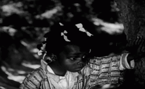a black and white po of a woman leaning on a tree