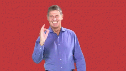a man standing against a purple backdrop while making the v sign