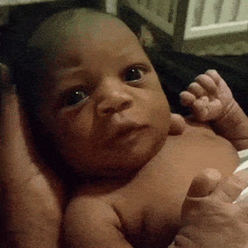 a black baby in a crib staring at the camera