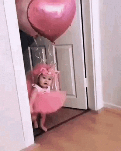 a little girl in purple is holding balloons while standing at the door