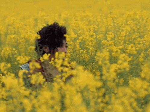 a woman sitting on the ground surrounded by flowers