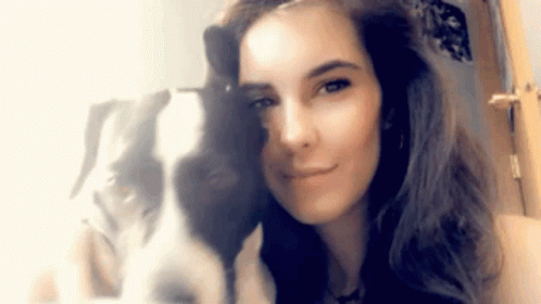 a woman is smiling while taking a selfie with her dog