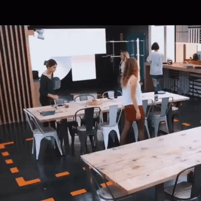 a room with tables, stools, and people standing in it
