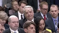 people wearing suits in a room and one is making a face