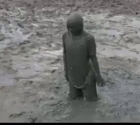 the man is walking through a muddy field