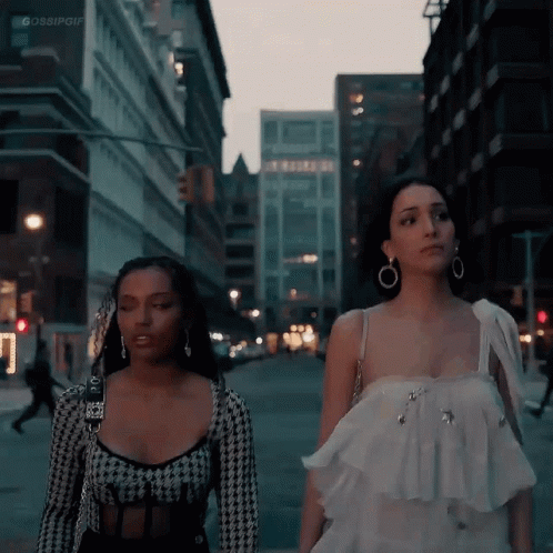 two young women walking along a city street at night
