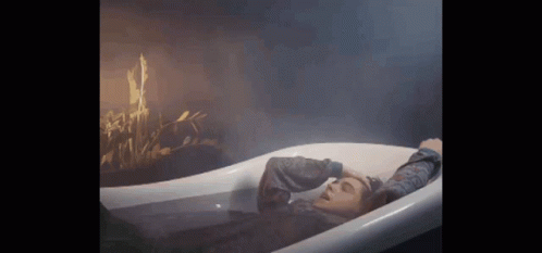 a woman laying in a bathtub with her head inside