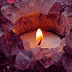 a candle in a bowl surrounded by crystal stones