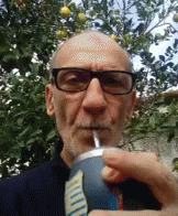 the man is holding a drink with blue googlying on his face