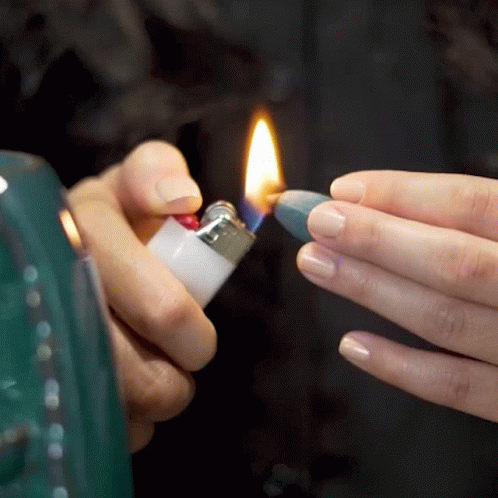 two hands hold a lighter that is lit