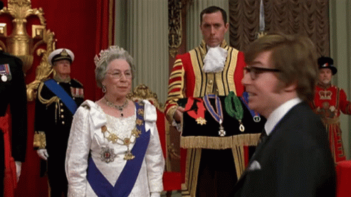 queen elizabeth talks to a gentleman in uniform and an official