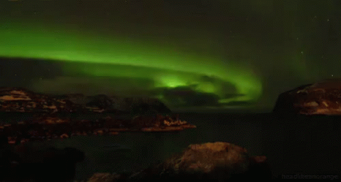 green light shines over the icebergs and ocean water