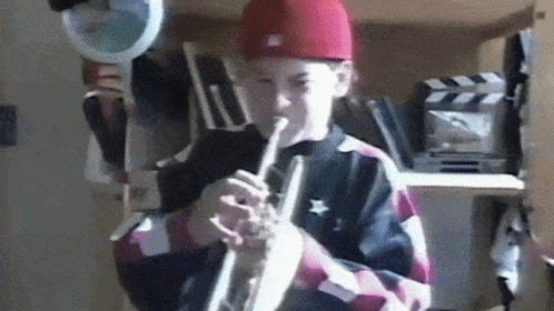 a boy in a purple hat and checkered shirt with a flute