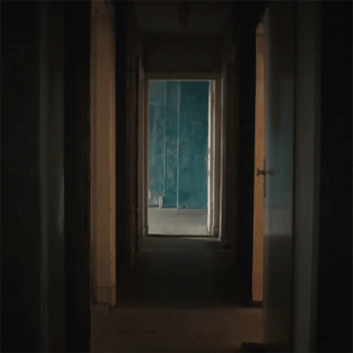 an empty hallway with yellow walls and light coming from the open door