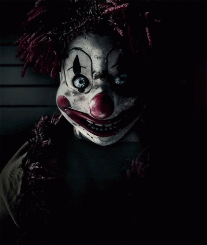 a creepy clown looks up in the darkness