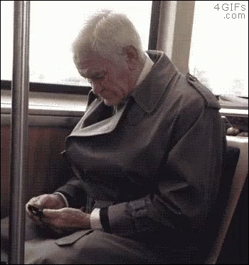 an old man on a bus looking at his cell phone