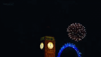 a clock tower decorated with lights and a firework in the background