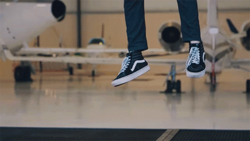 the feet of two persons in sneakers jumping off the tarmac