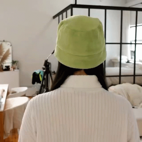 the back of a person with a green hat on their head