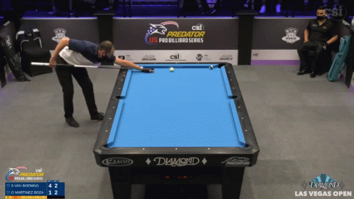 a man is on stage playing pool in a darkened arena