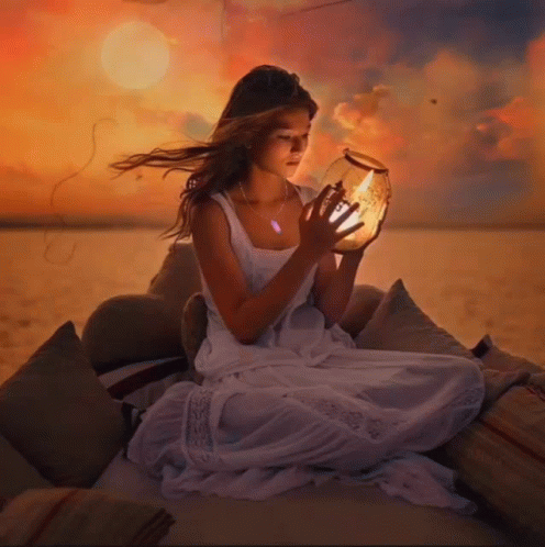 a girl is on a beach with a lite up candle in her hand