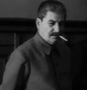 a man is standing in a room with a cigar in his mouth