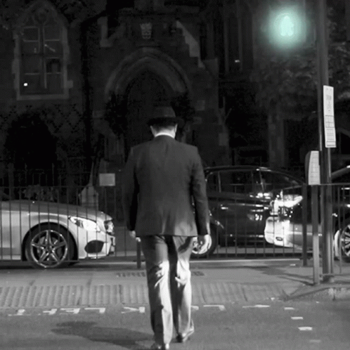 man in business suit walks across a cross walk
