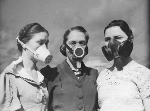 three women standing next to each other with gas masks on