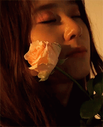 a woman with a flower is close to her face