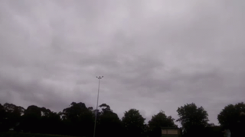 a plane flying in the cloudy gray sky