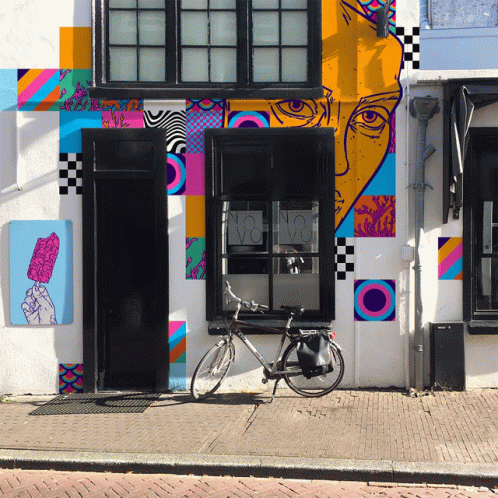 a bike parked in front of a wall with a large colorful mural on it