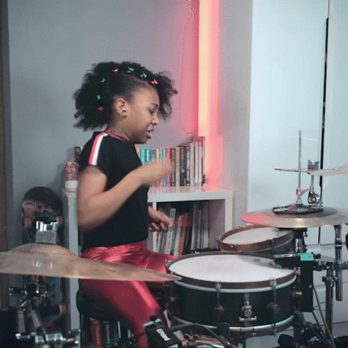 girl sitting behind the drum set on a stool