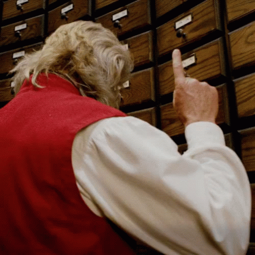 a person with an old man pointing to a row of drawers