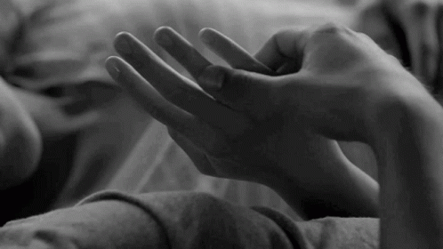 a black and white po of someones hand on the bed