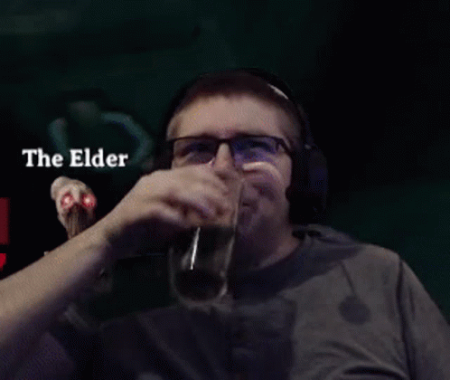 man drinking while wearing headphones and holding a glass