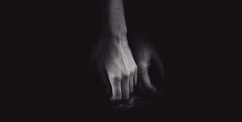 two hands in the dark reaching toward each other