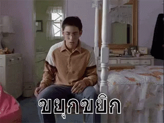 a person sitting in a bed with the words in thai written over it