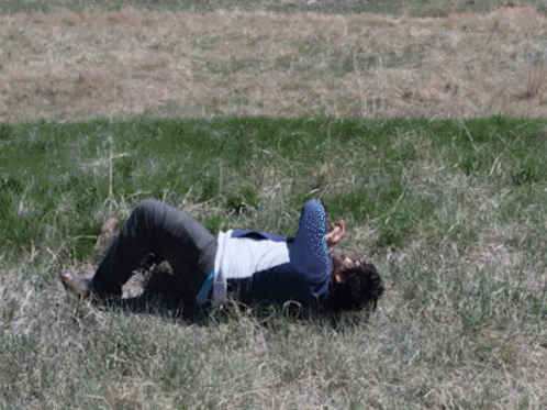 man with leg high laying in grass on his stomach