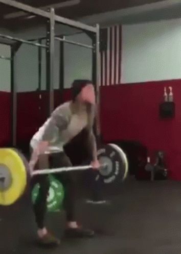 a man lifts up his barbell in a crossfit gym
