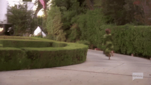 a young child is running toward a circular garden