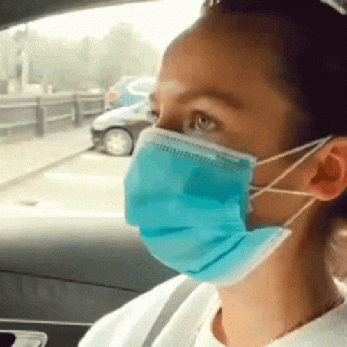 a man in a car wearing a surgical mask