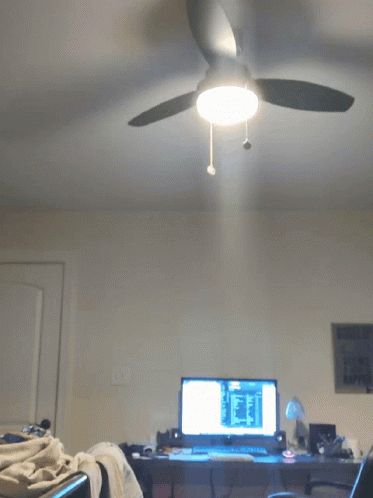 a bedroom with a ceiling fan in front of a desk
