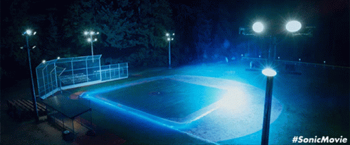 a baseball field lit by street lights at night