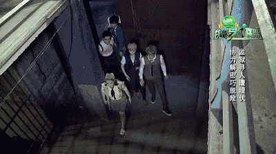 the screens from above shows a group of three people walking in a dark tunnel