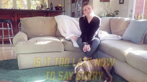 a woman sitting on top of a couch next to a dog
