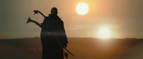 a person in silhouette holding two spears while looking out towards the sky