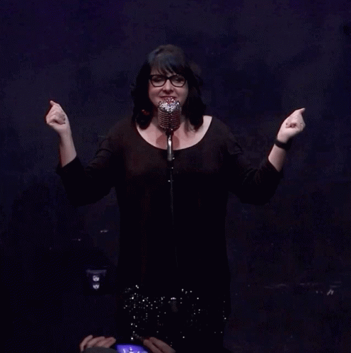 a woman standing behind a microphone with her arms outstretched