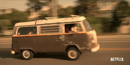 a small vw bus with a dog inside drives down the street